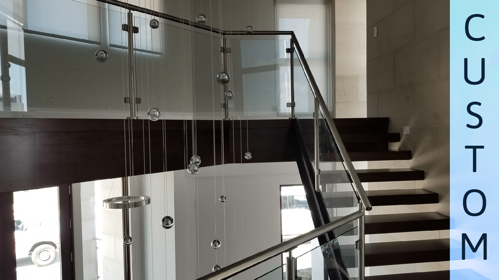 A staircase with a glass railing and the word custom on the bottom
