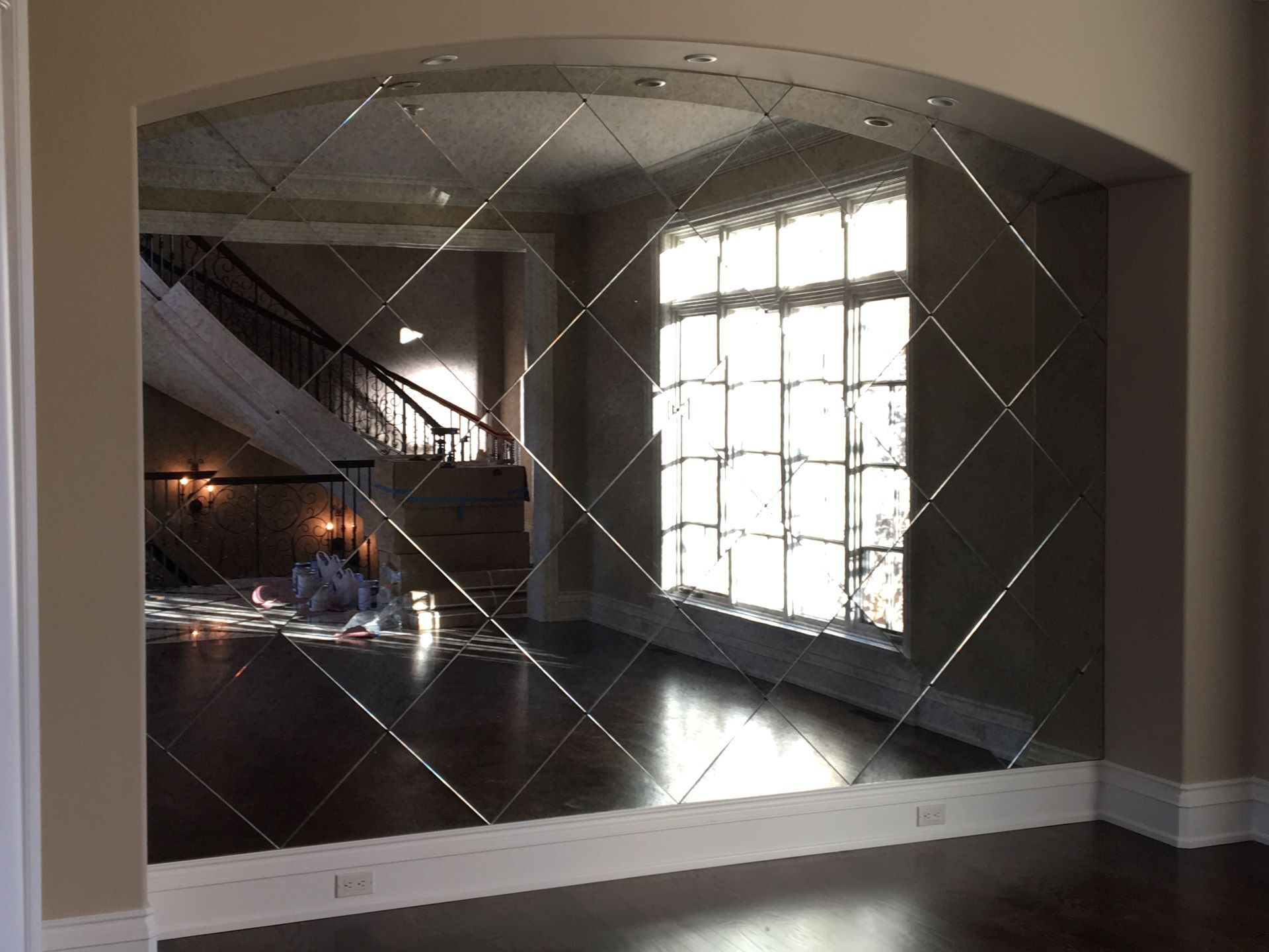 A large mirror in a room with a staircase in the background