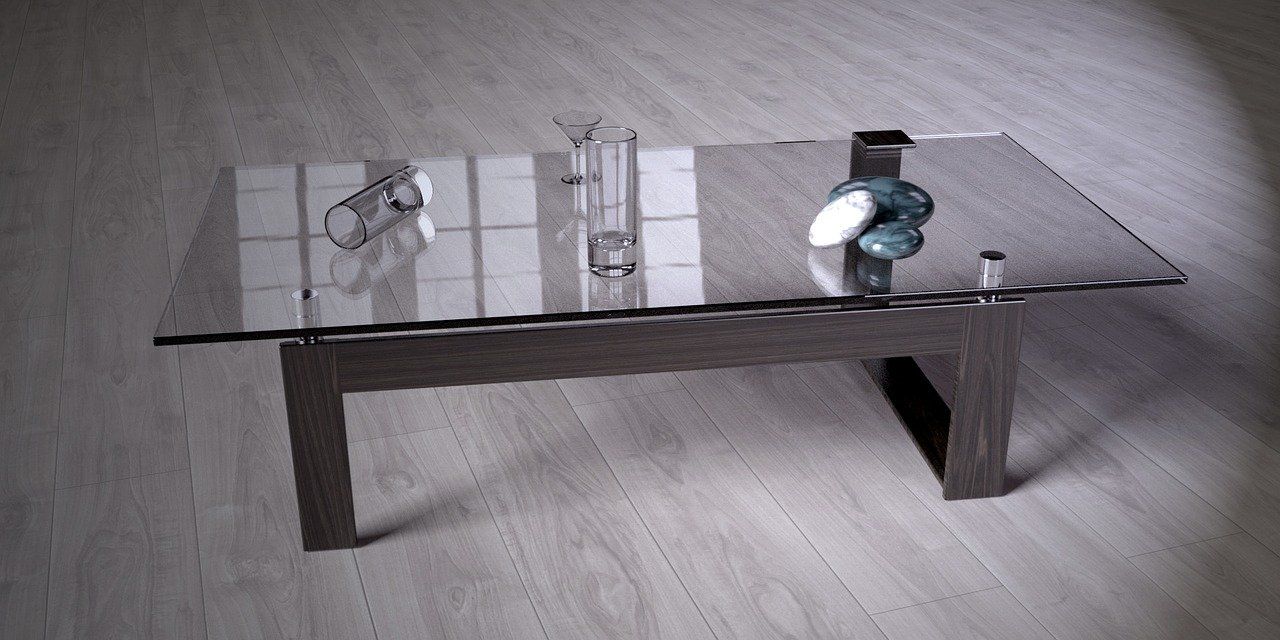 A glass coffee table with a vase on top of it