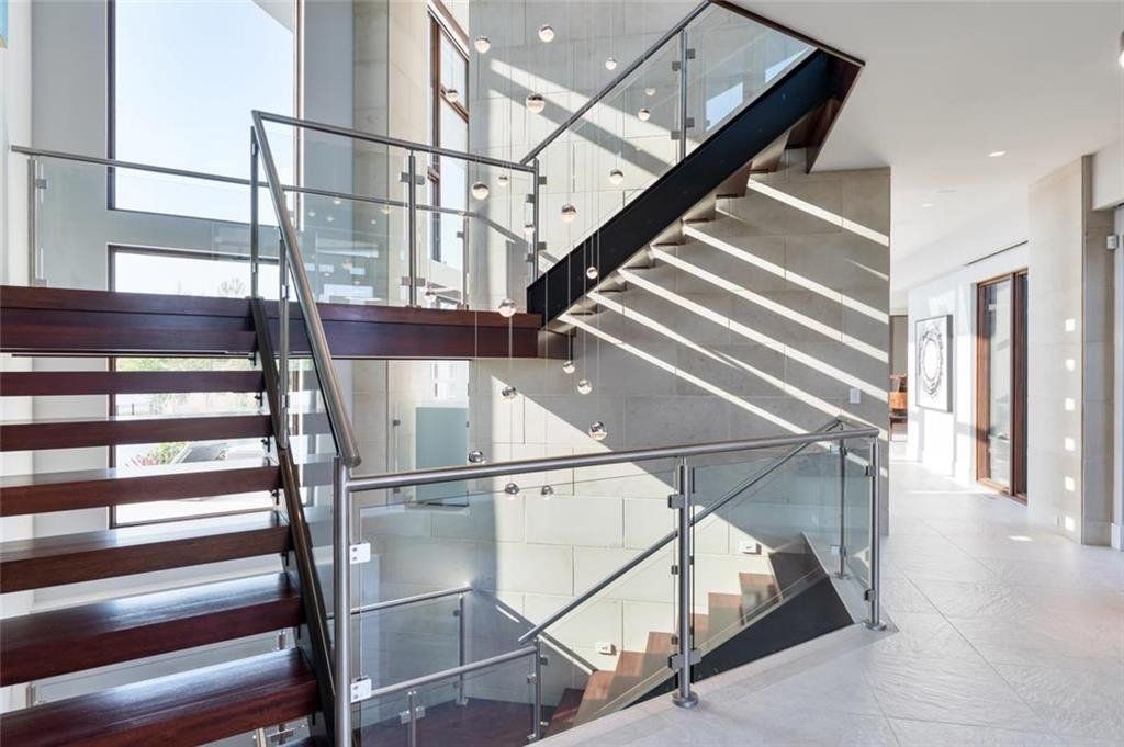 A modern staircase with a glass railing and wooden steps