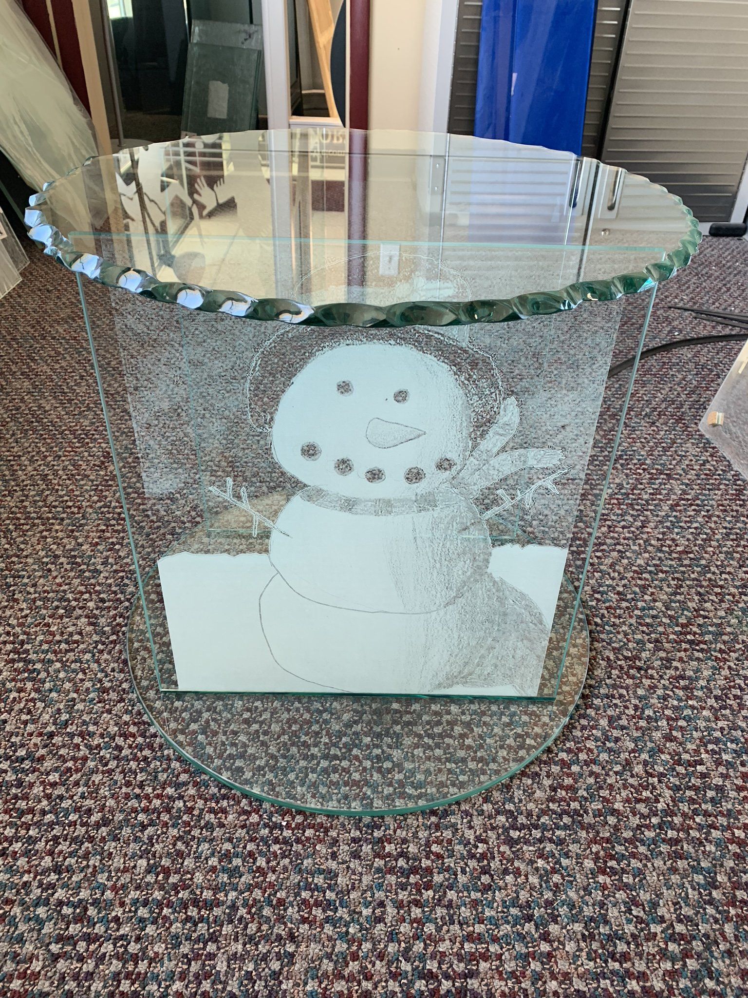 A glass bowl with a snowman on it is sitting on a carpet.