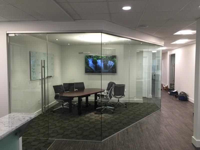 A conference room with a glass wall and a table and chairs.