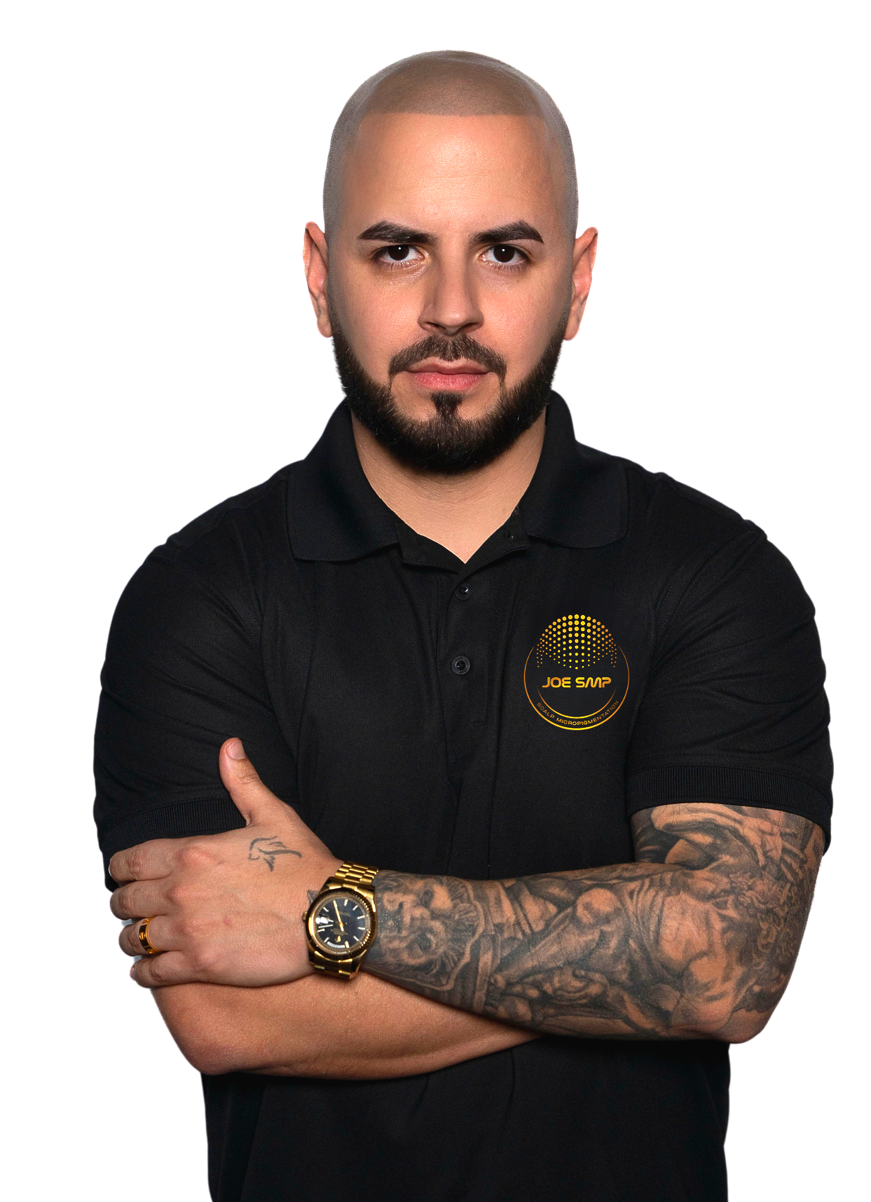 Man with a shaved head and beard in a black shirt, arms crossed, tattoos visible.