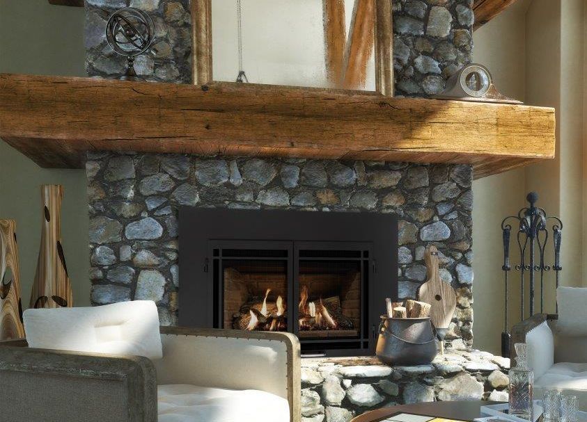 Cozy fireplace with a stone surround, a wooden mantel, and a burning fire, in a rustic living room.