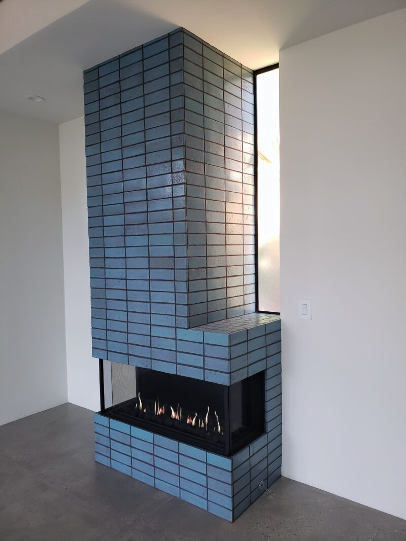 Living room with a fireplace, a bull head decoration above it, and dark gray stonework. A bookshelf and coffee table are also visible.