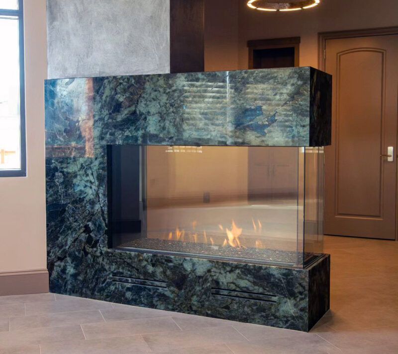 Living room with a fireplace, a bull head decoration above it, and dark gray stonework. A bookshelf and coffee table are also visible.