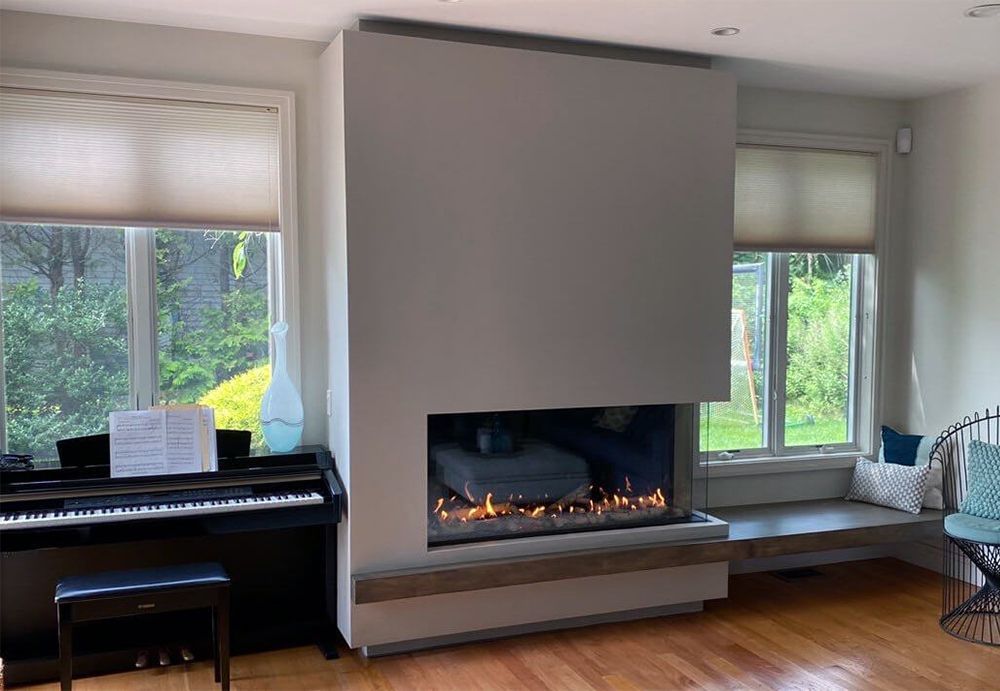 Living room with a fireplace, a bull head decoration above it, and dark gray stonework. A bookshelf and coffee table are also visible.