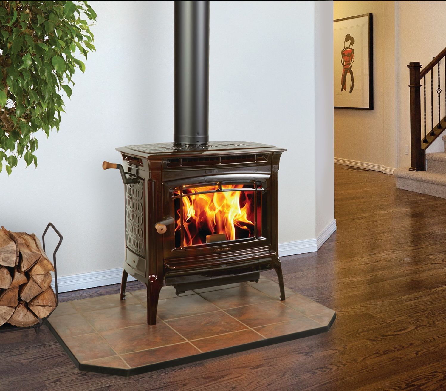 A wood-burning stove with a roaring fire sits on a tiled hearth in a home. Stacked firewood rests nearby.