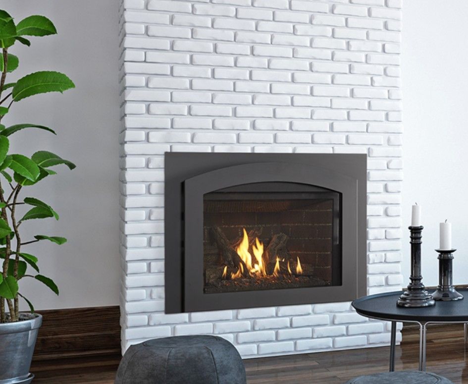 A gas fireplace with flames burning inside a black metal frame set into a white brick wall.