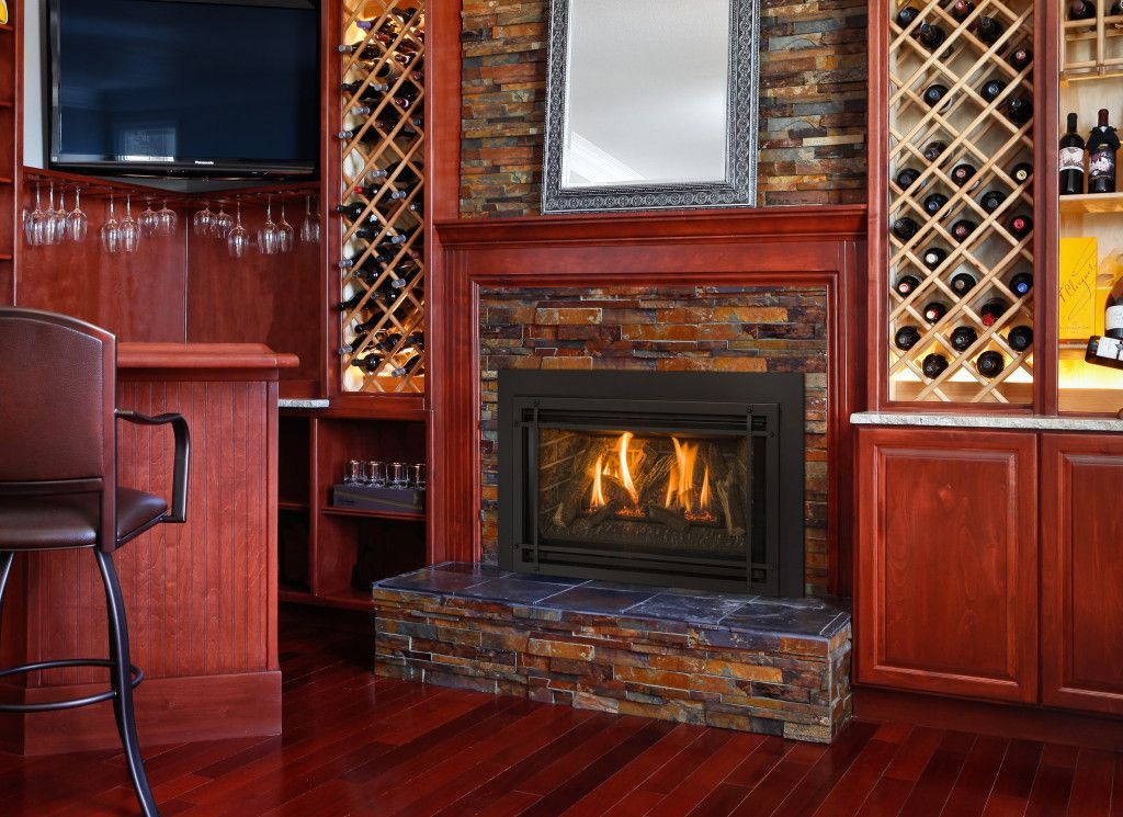 A cozy bar area with a fireplace, wine racks, and a built-in TV. The space features dark wood and stone accents.