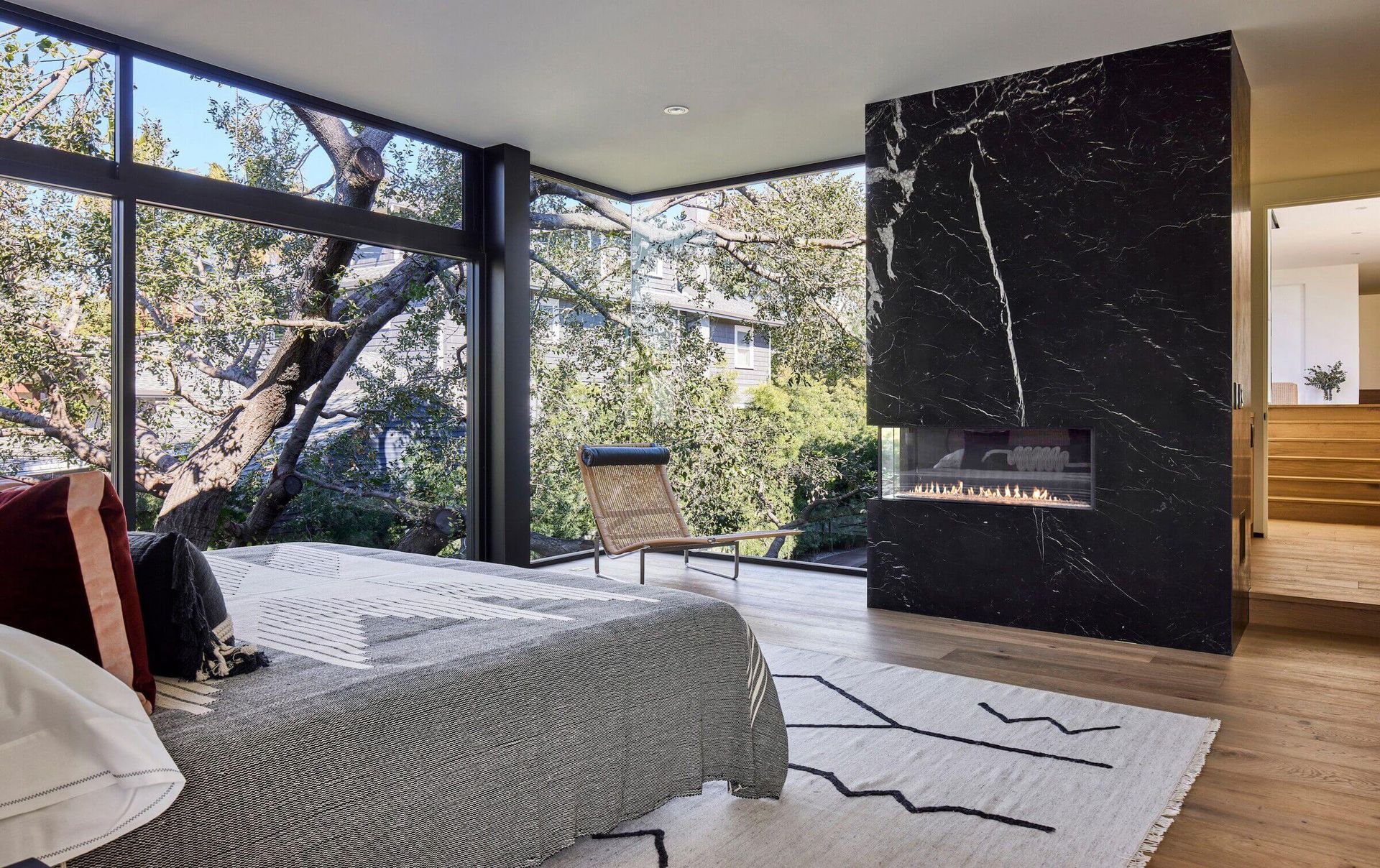 Fireplace with lit flames, set in a stone wall. A marble shelf supports art and decor; a living room setting.