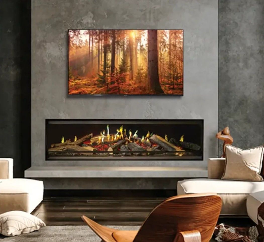 Electric fireplace mounted on a wood-paneled wall with a bookshelf. The fireplace shows colorful flames, inside a modern living space.