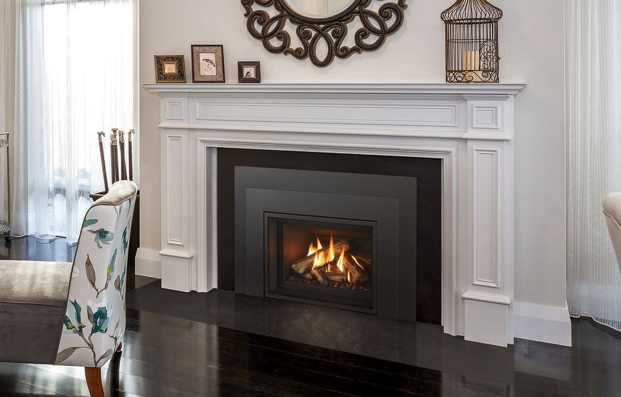A fireplace with a dark firebox, surrounded by a white mantel. Decorations include a mirror, pictures, and a birdcage.