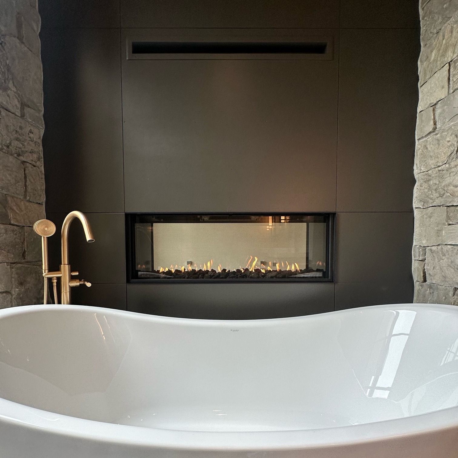 Living room with a fireplace, a bull head decoration above it, and dark gray stonework. A bookshelf and coffee table are also visible.