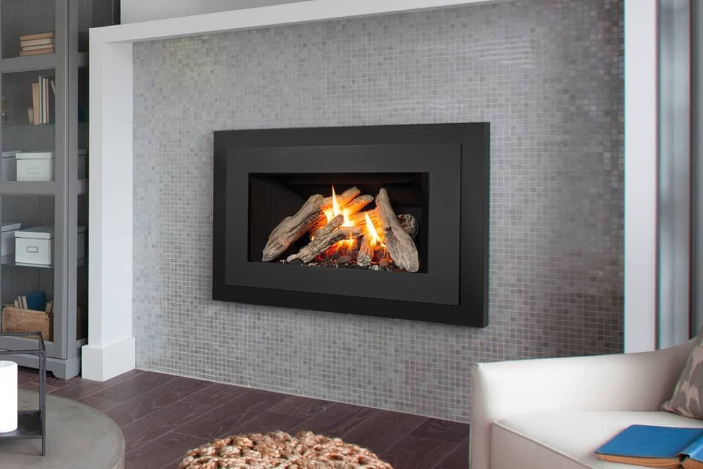 A fireplace with burning logs is set into a tiled wall, framed in black. A gray couch and a bookshelf are visible.