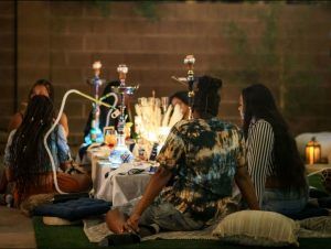 A group of people are sitting around a table with hookahs.