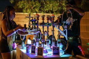 A man and a woman are standing next to a table filled with hookahs.