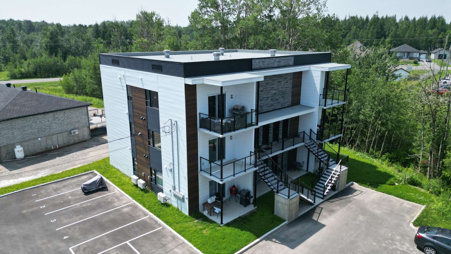 Immeuble moderne de trois étages avec balcons et escaliers extérieurs.
