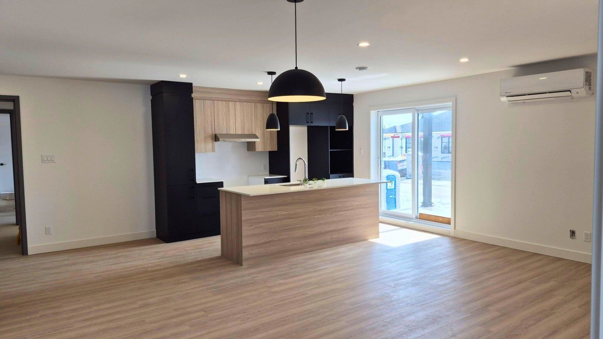 Cuisine et séjour à aire ouverte avec parquet, armoires en bois clair.