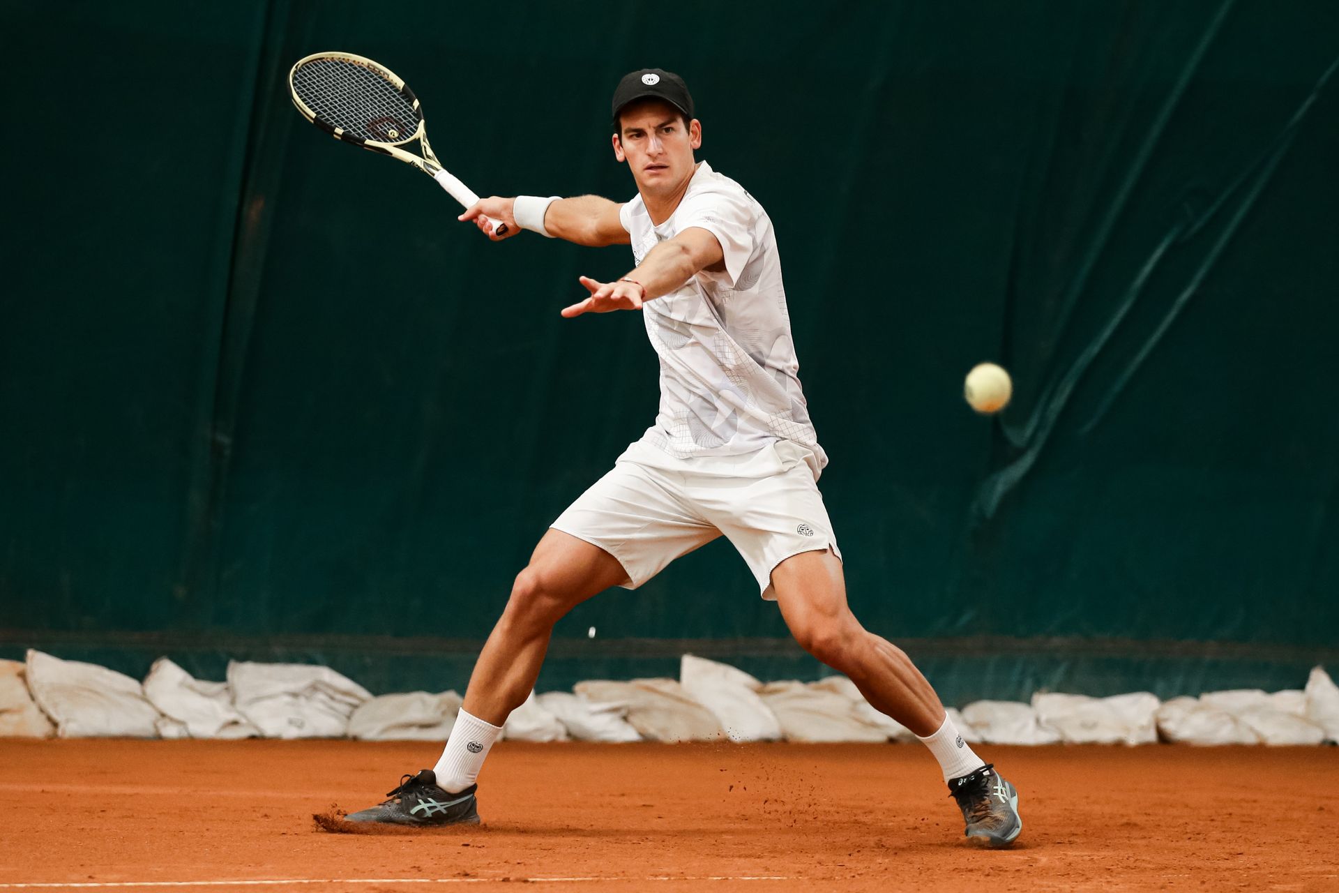 A woman is playing tennis on a clay court.