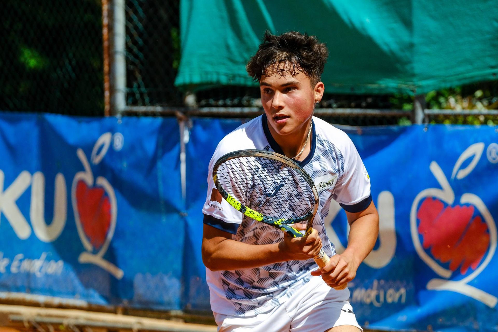 A young man is holding a tennis racquet on a tennis court.