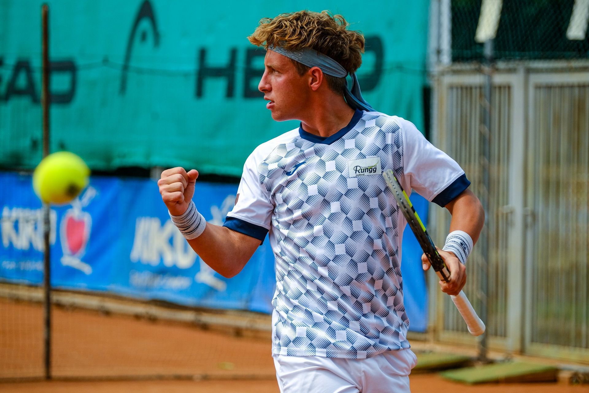 A young man is holding a tennis racquet on a tennis court.