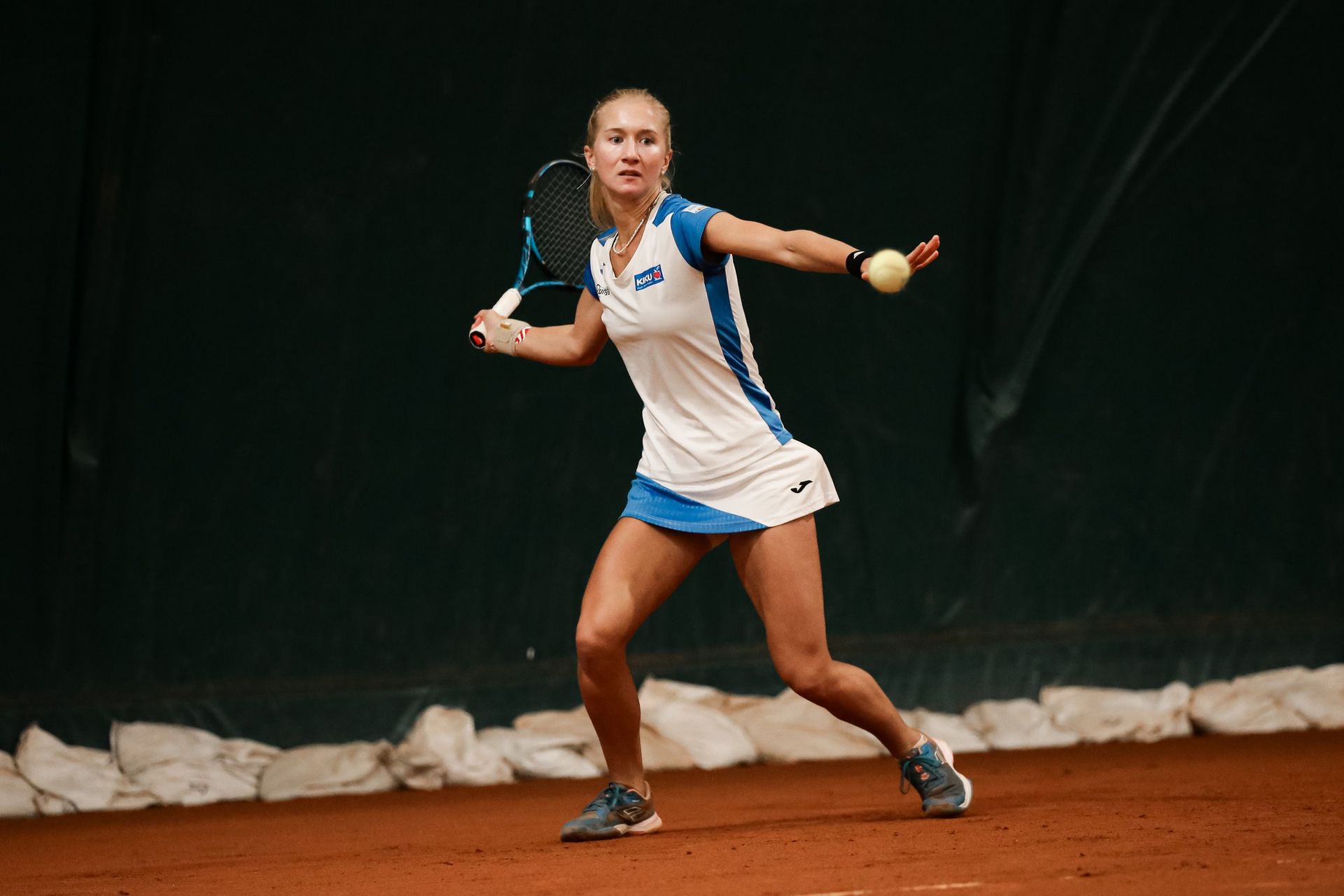 A woman is playing tennis on a clay court.
