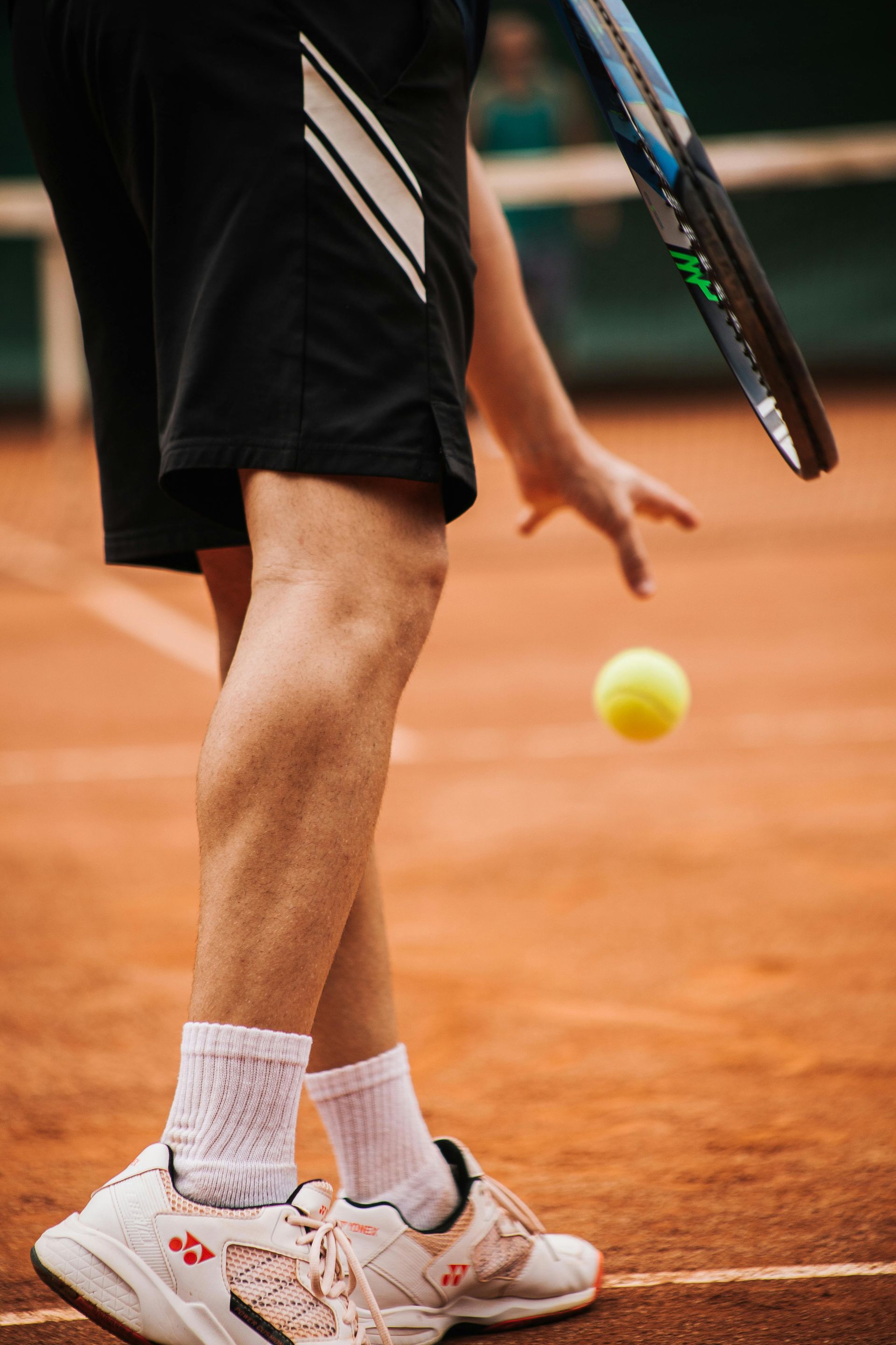 A person is holding a tennis racket and a tennis ball on a tennis court.