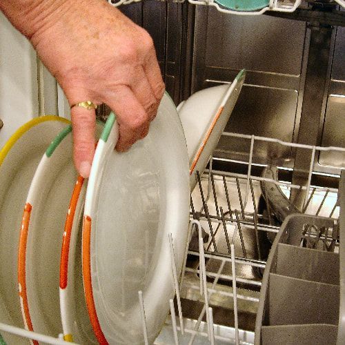 A person is taking a plate out of a dishwasher