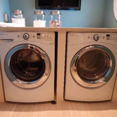 Two washers and dryers are sitting next to each other in a laundry room.