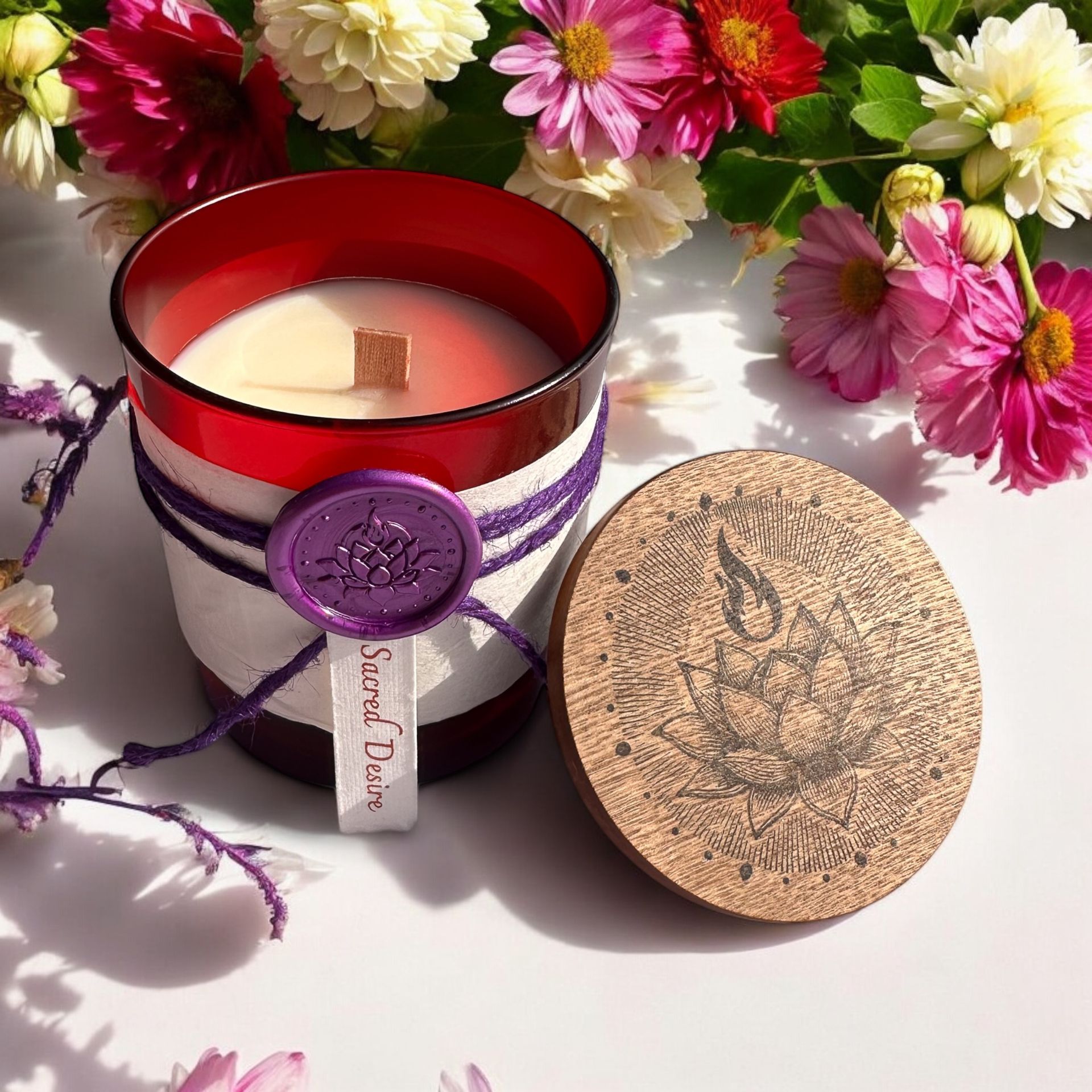 Open Sacred Desire candle by Eldara, surrounded by daisies and roses. Infused with peach moonstone and rhodonite to inspire passion, beauty and heart-led intention.
