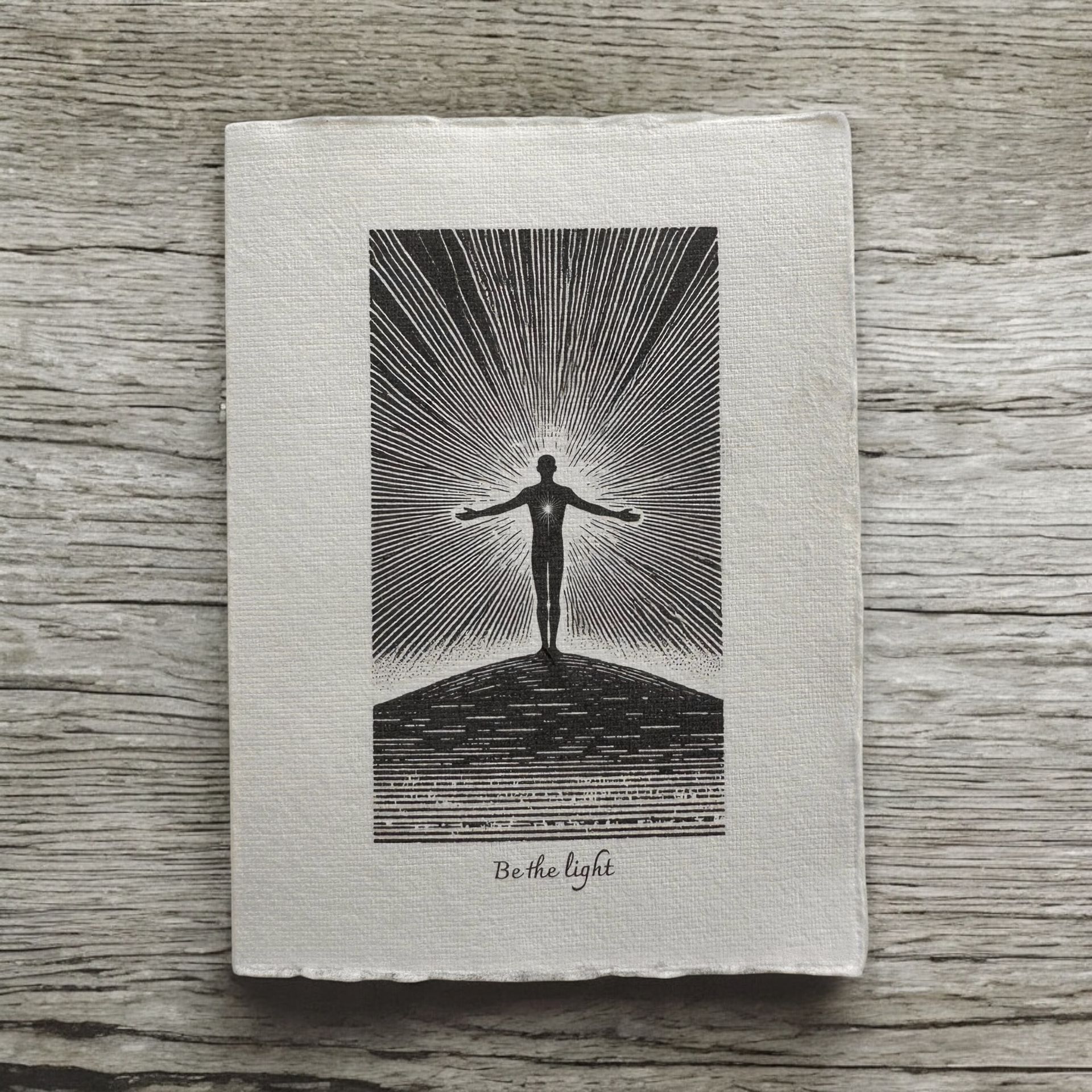 “Be the Light” greeting card by Eldara, featuring a silhouette of a person with arms outstretched. Printed on handmade paper to inspire hope and inner radiance.