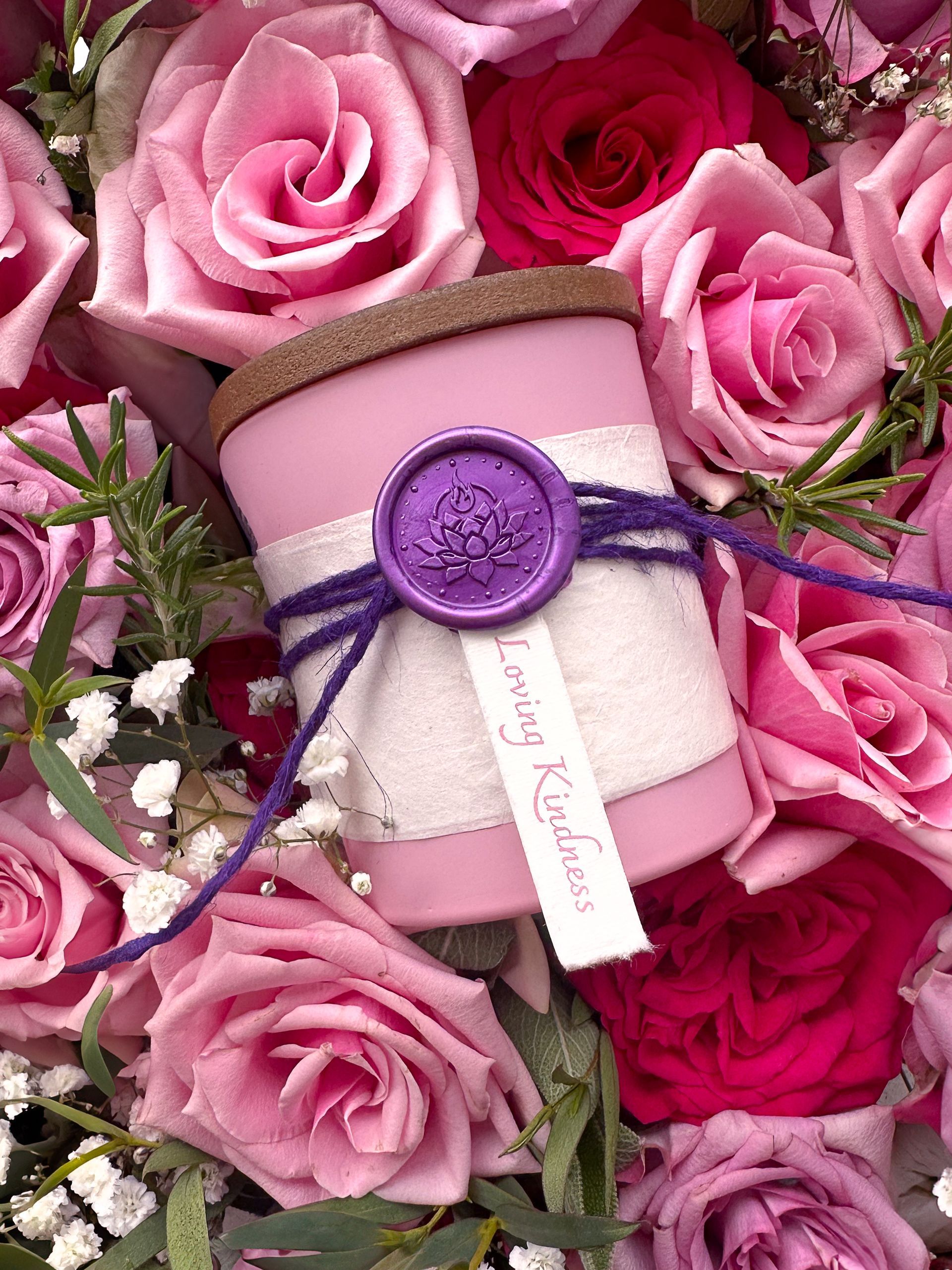 Loving Kindness candle by Eldara nestled in a bed of pink roses. Infused with rose quartz and sacred oils to nurture love, tenderness and emotional healing.