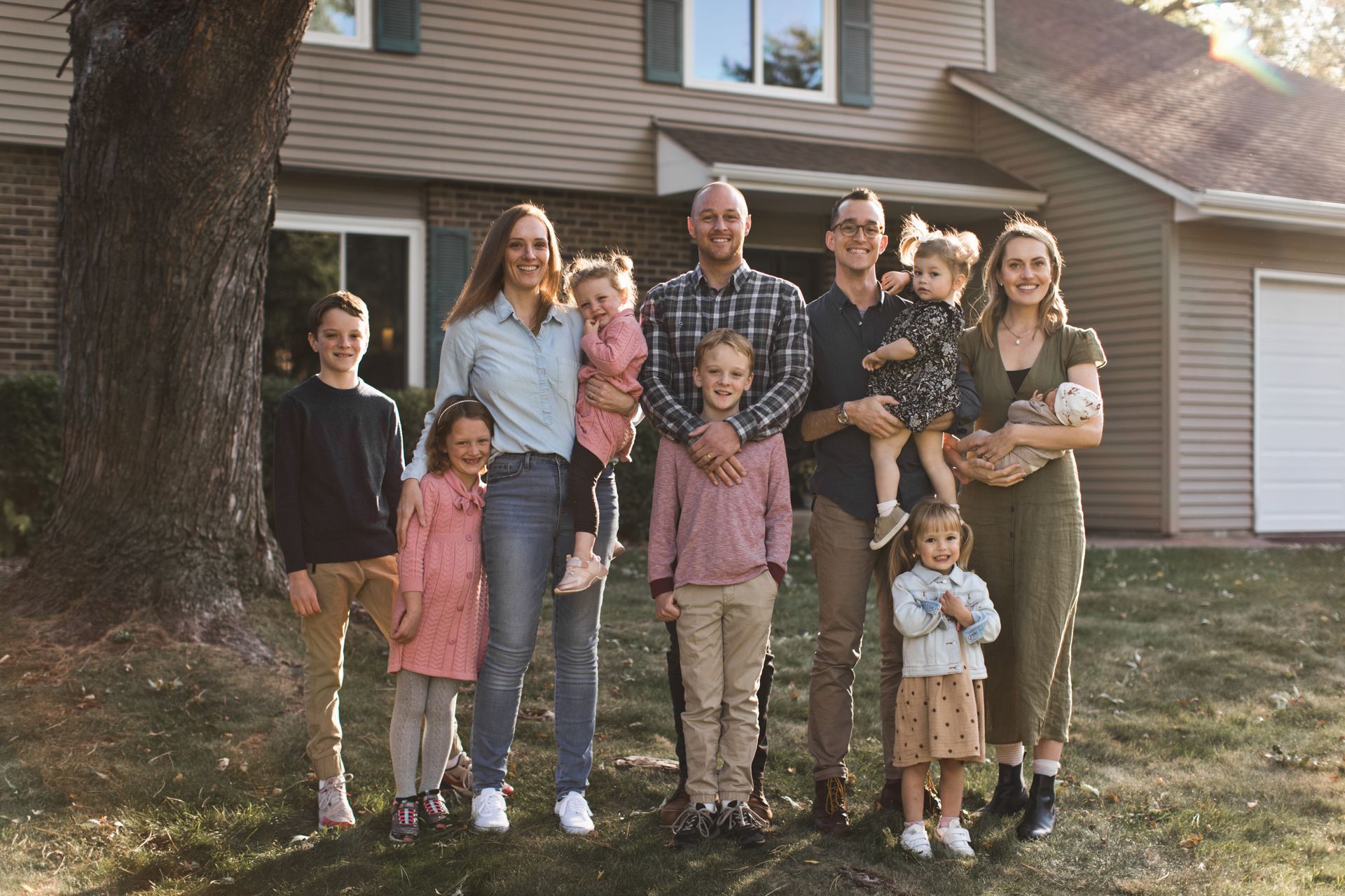 Family of eleven poses in front of a two-story house.