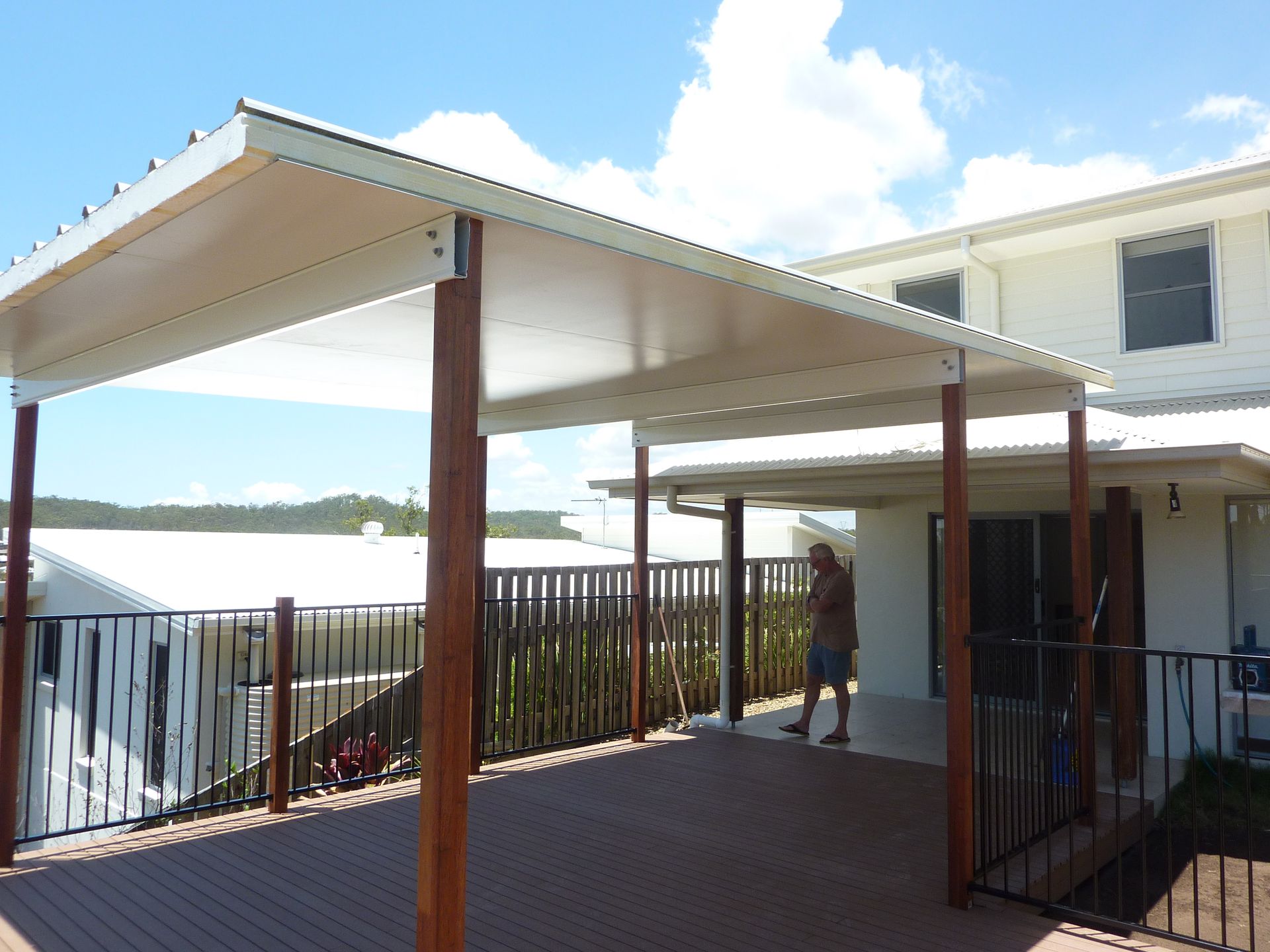 Deck with overhead canopy, wooden posts, and a person standing by the house. Sunny outdoor scene — Bob Ryan's Home Improvements & Construction Pty Ltd in Beecher, QLD