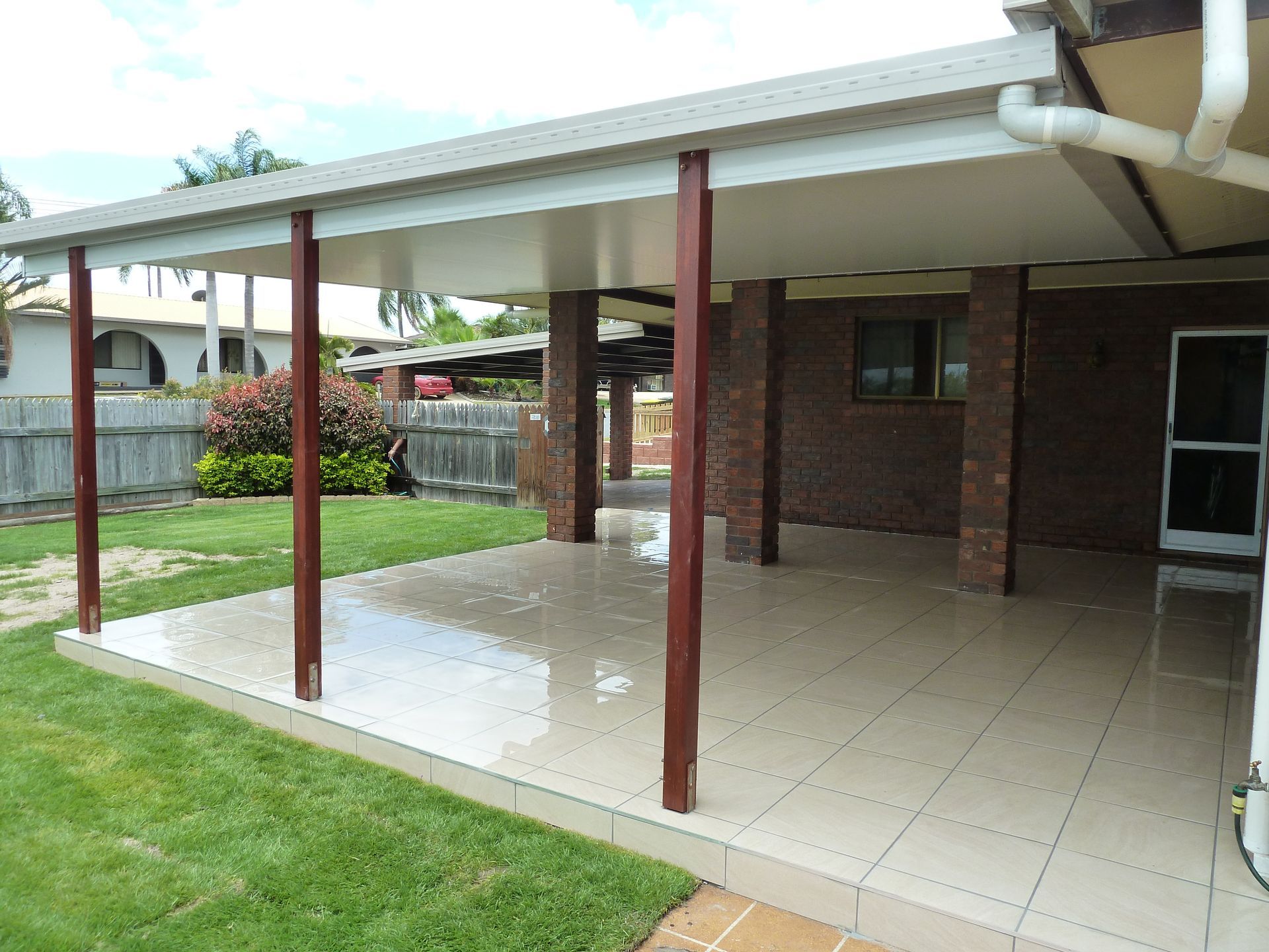 Covered patio with brown columns, beige tiles, and green grass — Bob Ryan's Home Improvements & Construction Pty Ltd in Beecher, QLD
