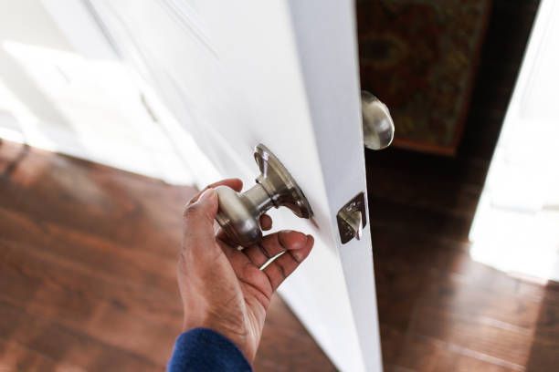Close-up of unrecognizable woman with her hand on interior doorknob opening door.