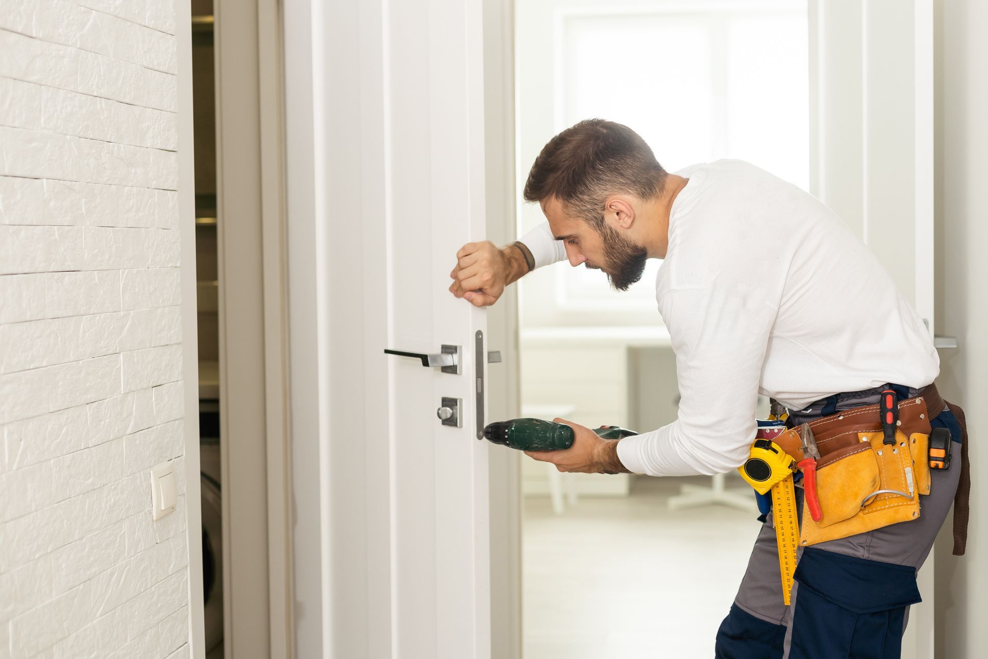 Skilled handyman repairing front door lock at home entrance.