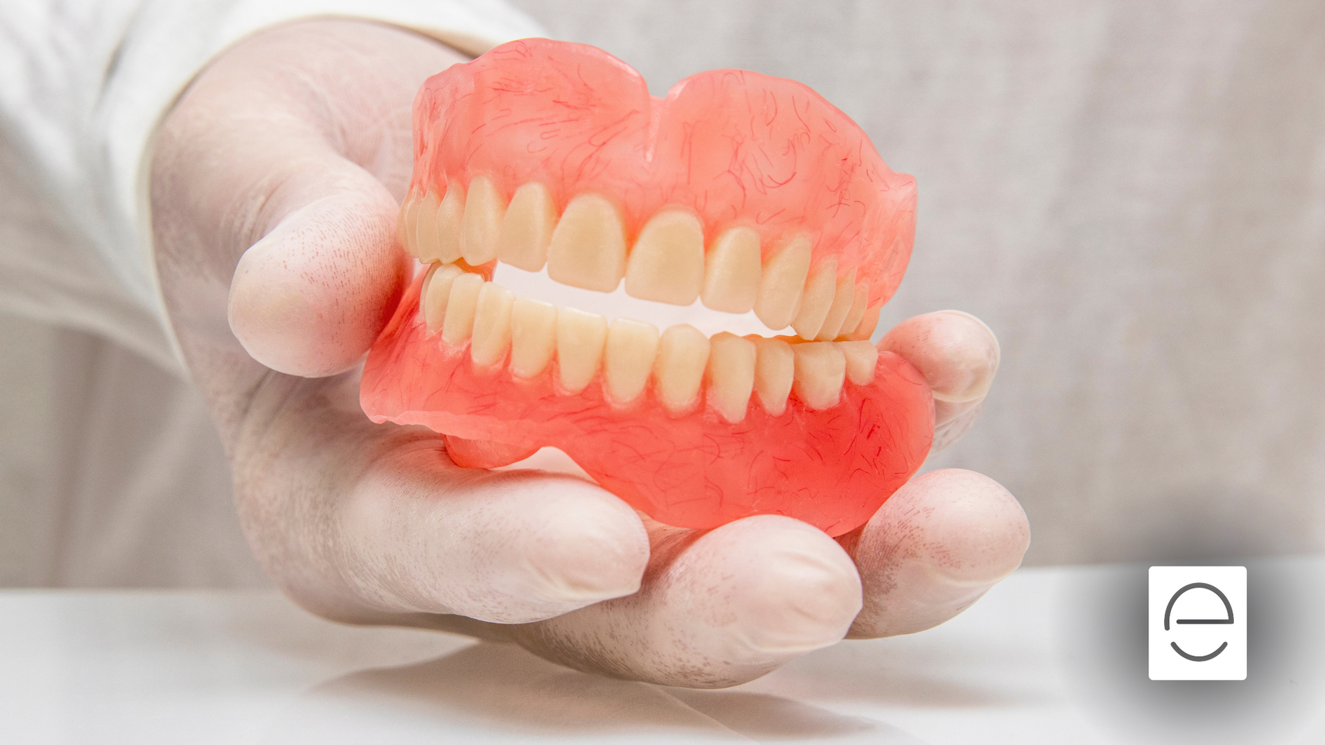 A person is holding a denture in their hand.