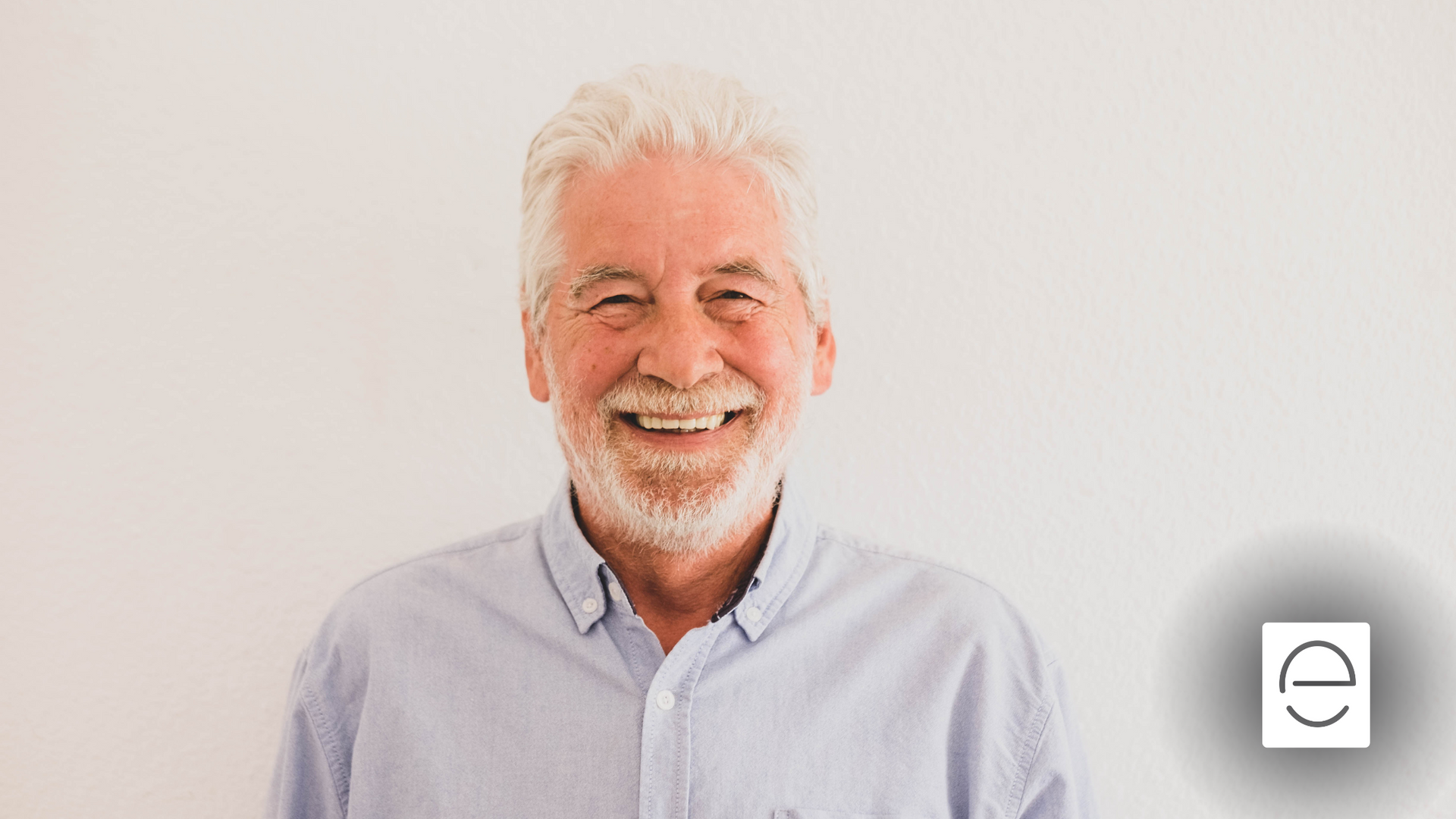 An older man with a beard is smiling for the camera.