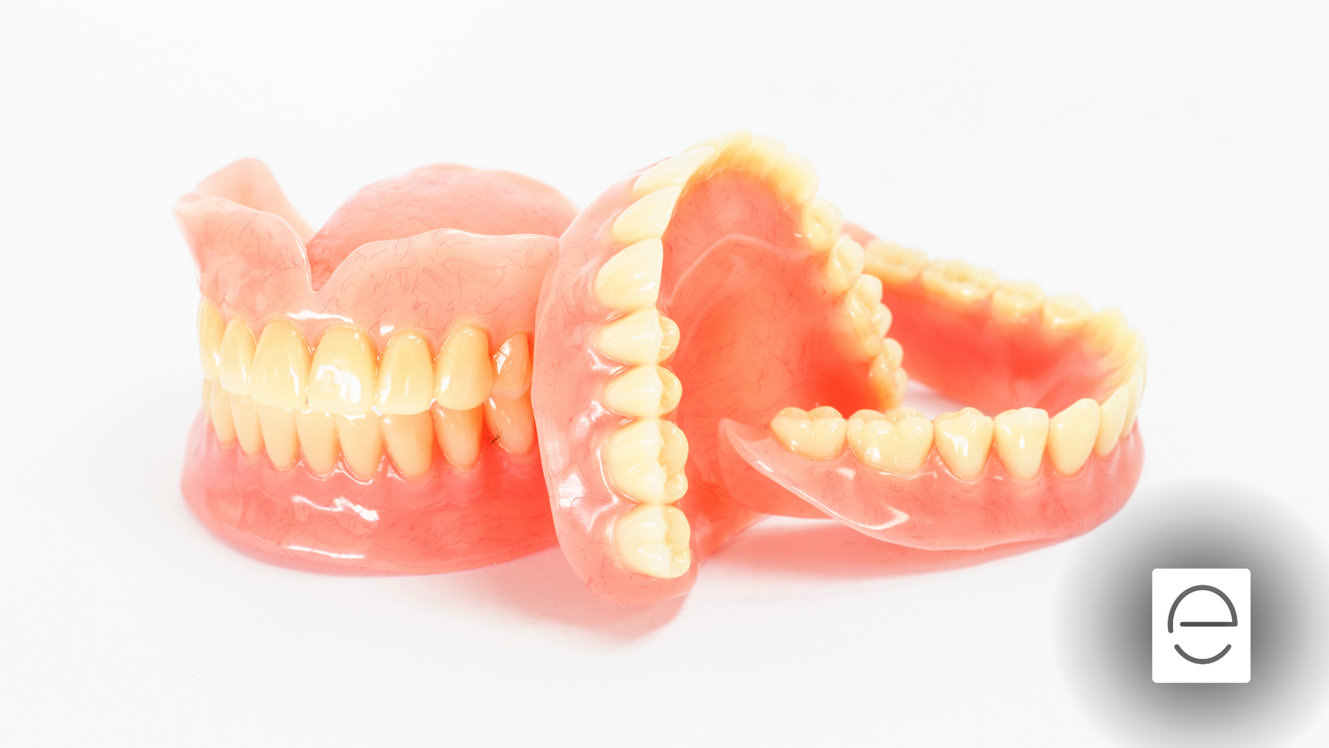 A pair of dentures sitting on top of each other on a white surface.