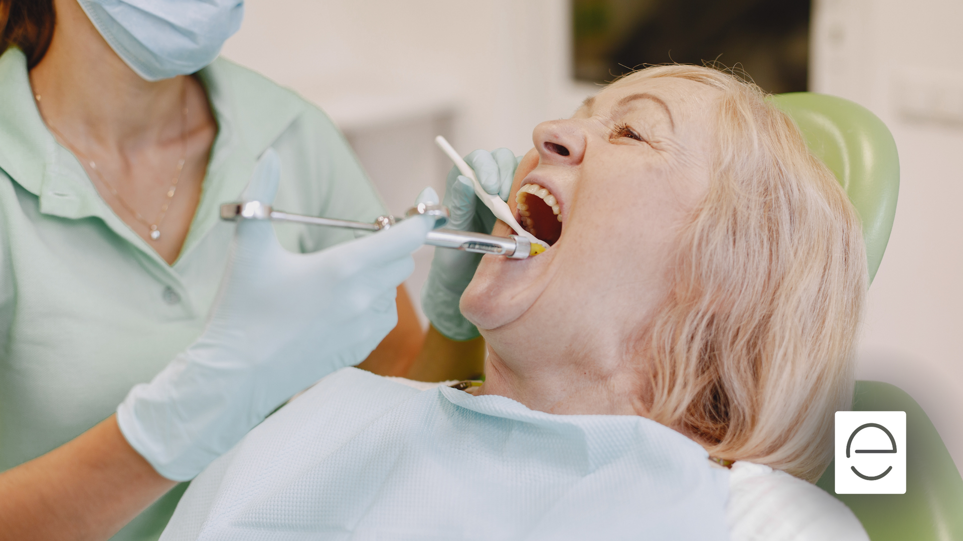 An elderly woman is having her teeth examined by a dentist.