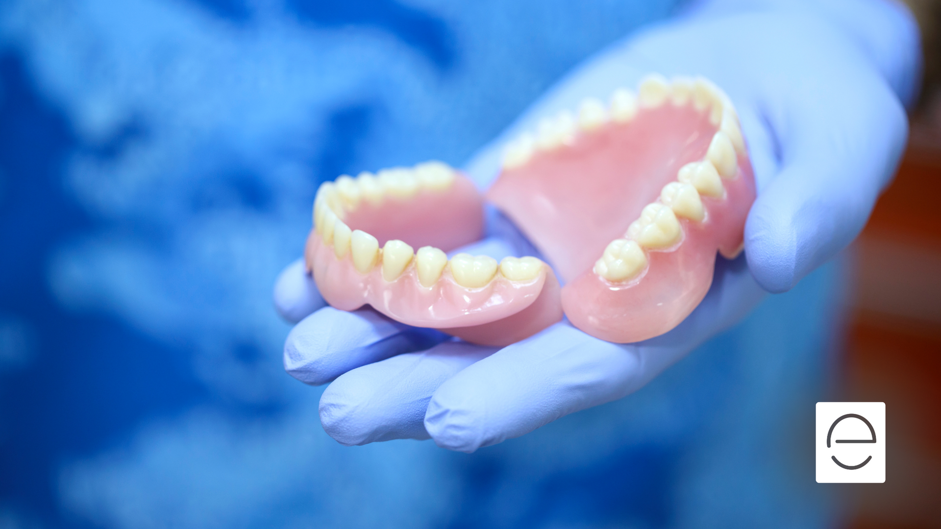 A person is holding a pair of dentures in their hands.