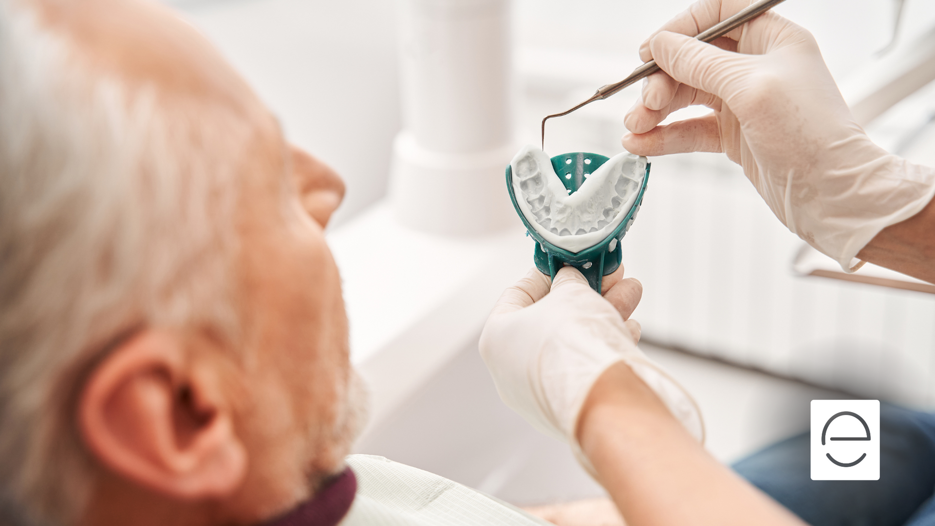 A man is sitting in a dental chair while a dentist examines his teeth.