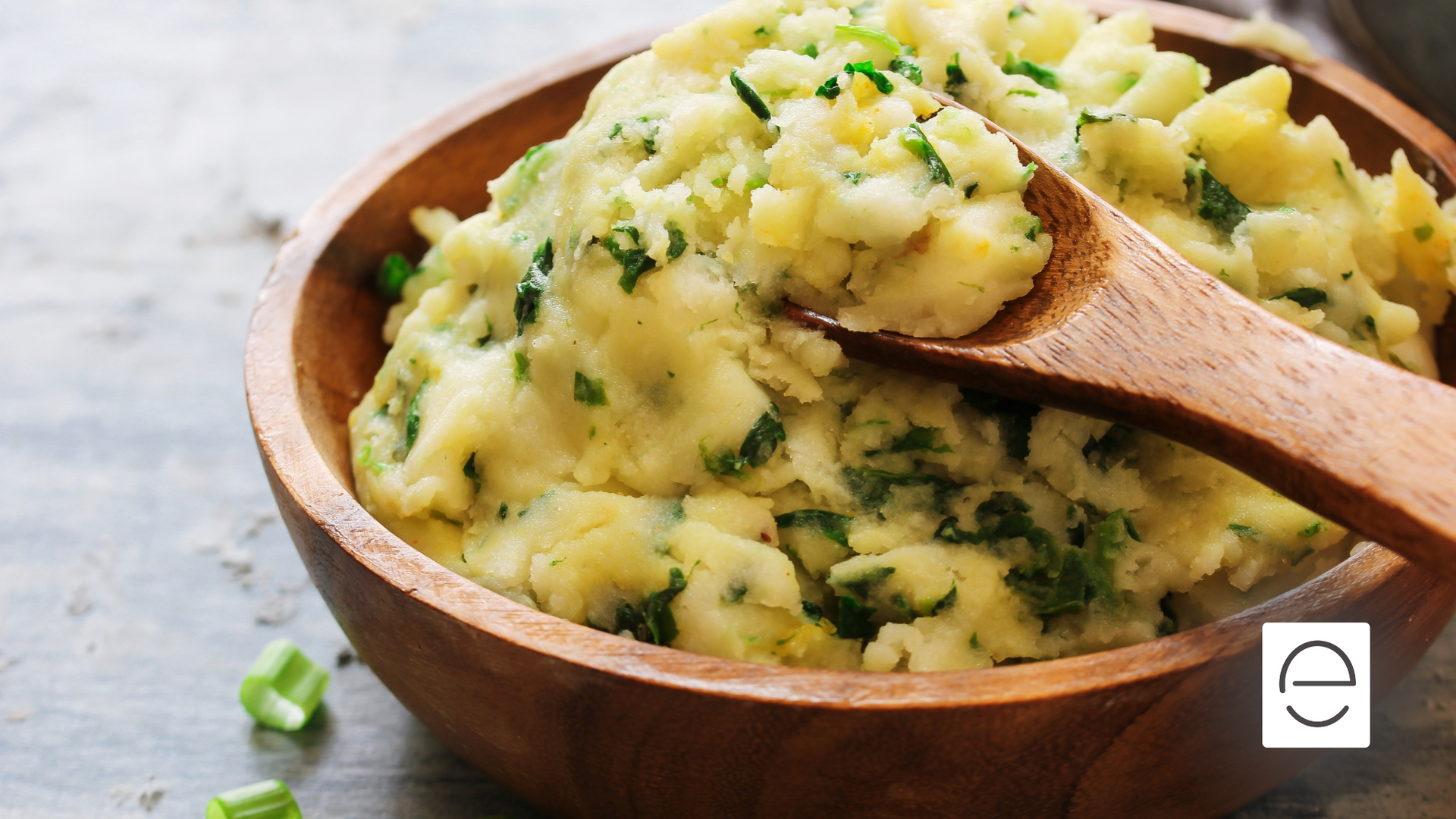 A bowl of mashed potatoes with a wooden spoon in it.