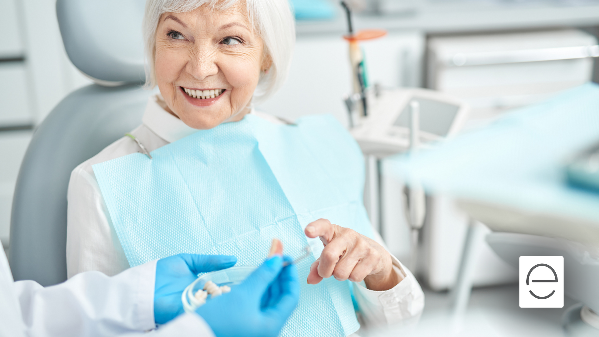 An elderly woman is smiling while sitting in a dental chair.