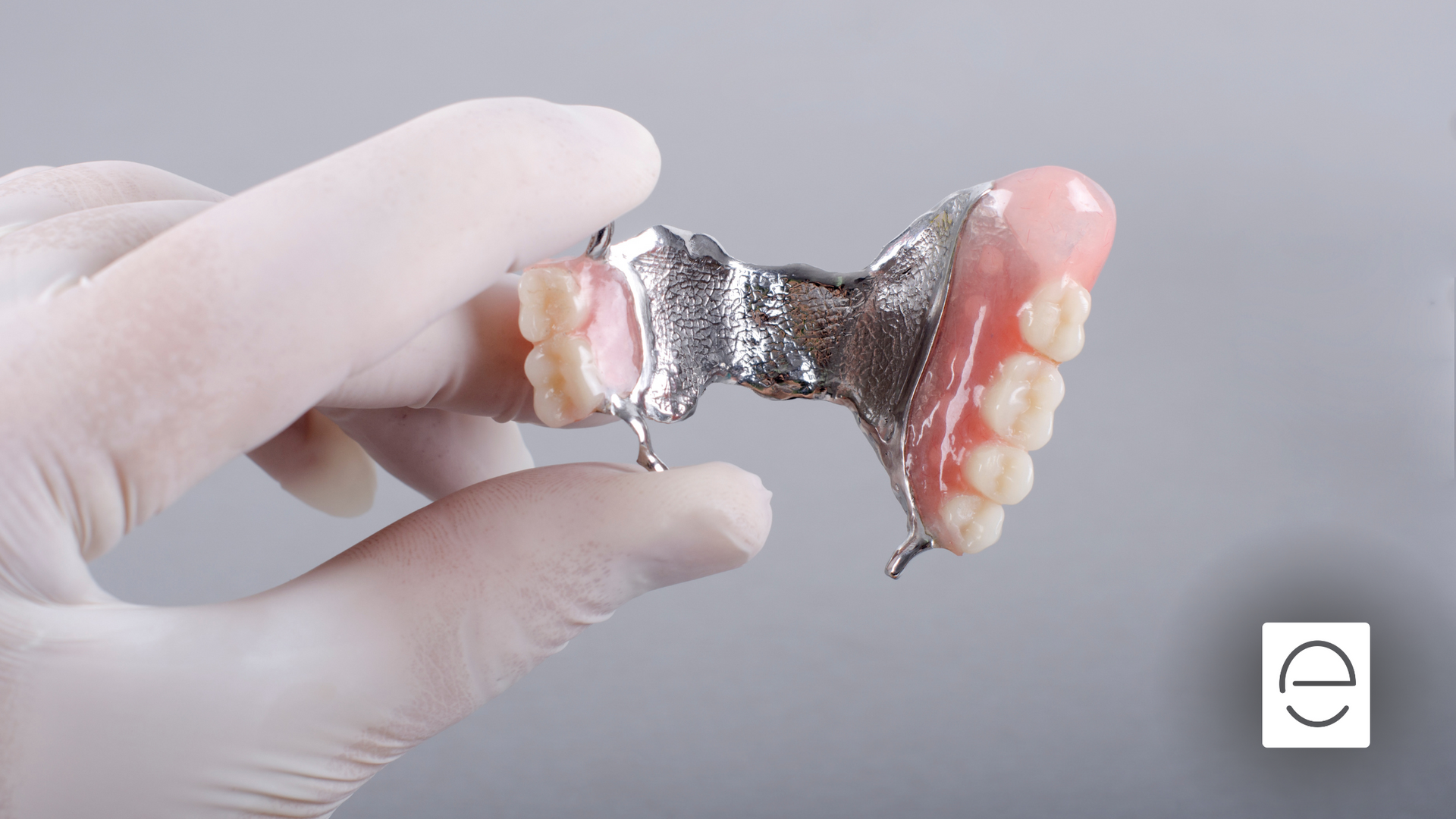 A person is holding a denture in their hand.