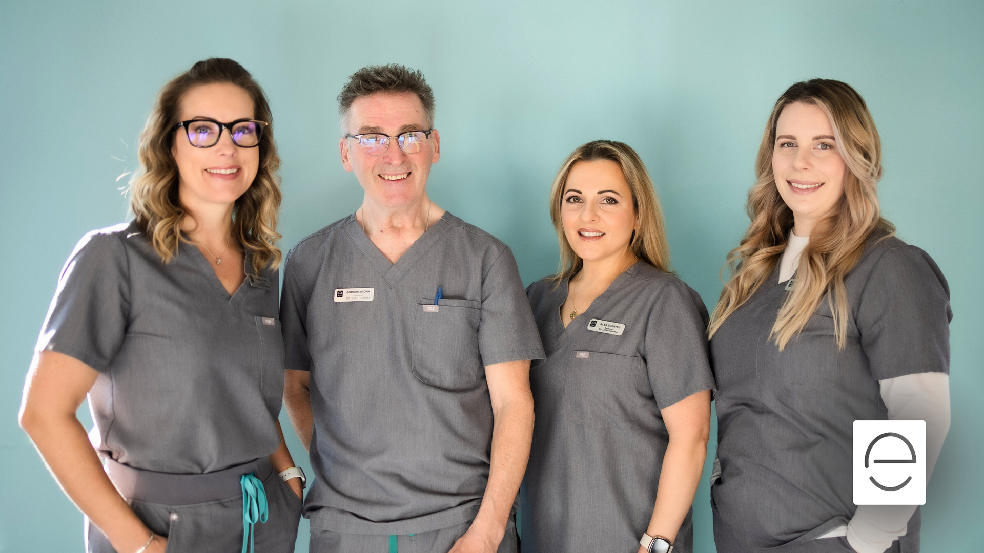 A group of people wearing scrubs are posing for a picture.