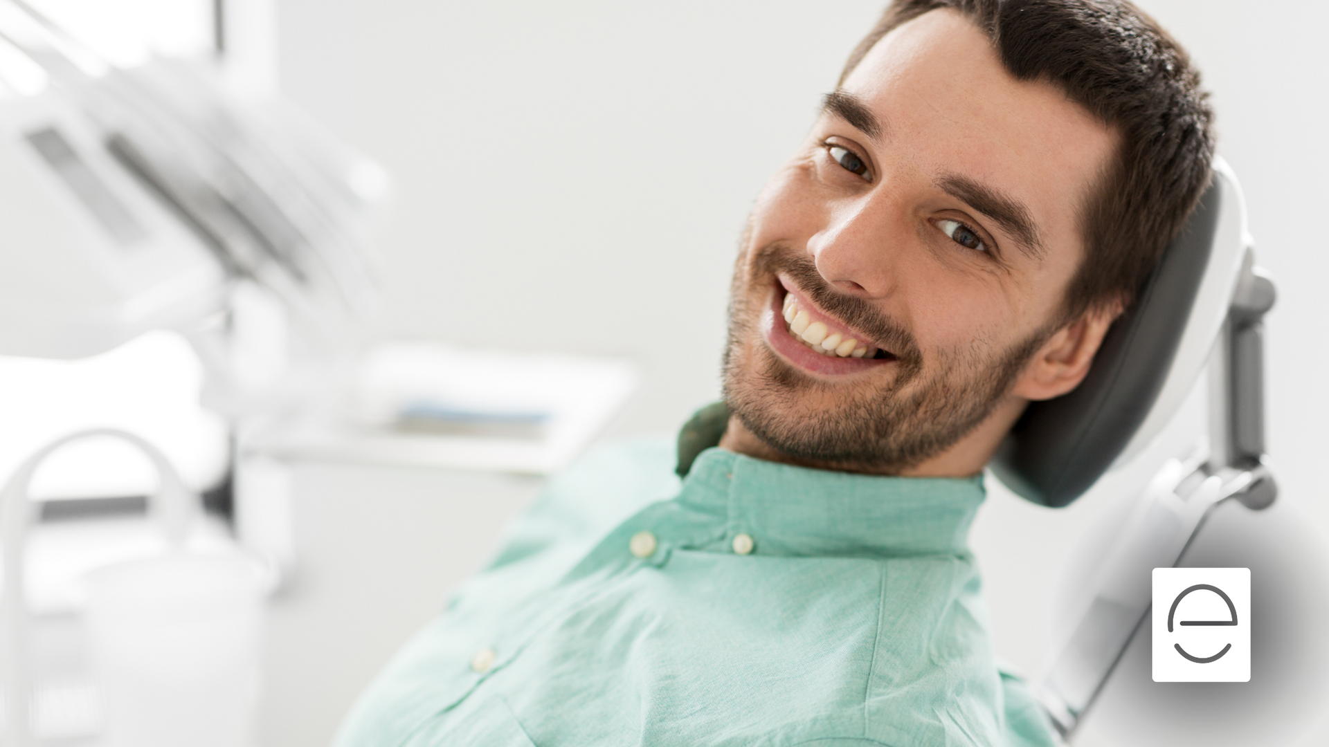 A man is smiling while sitting in a dental chair.