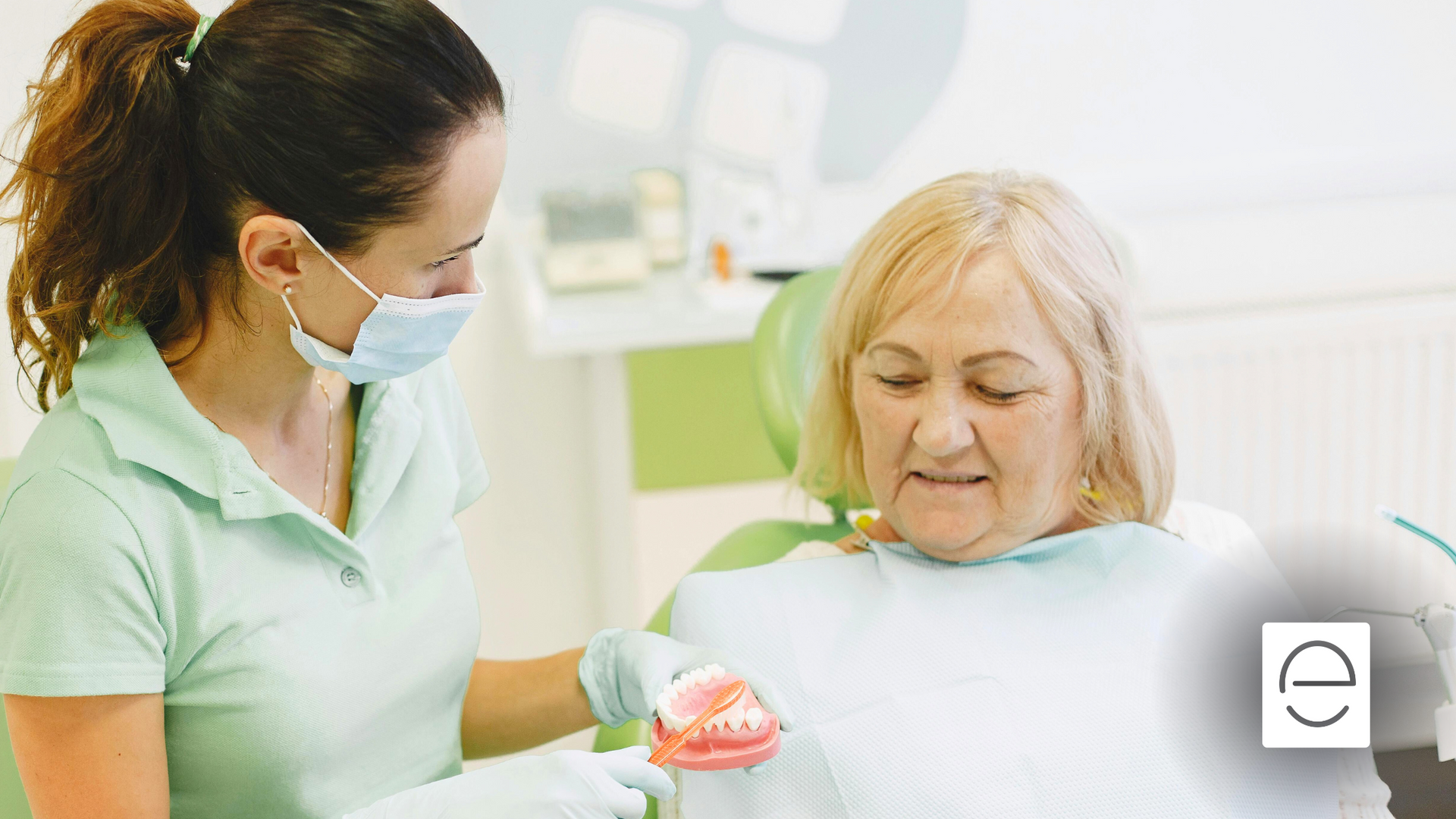 A woman is sitting in a dental chair while a dentist examines her teeth.